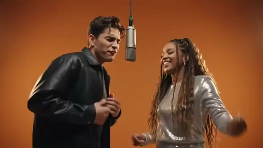 A man in a leather jacket and a woman in a sequin top dancing at the mic